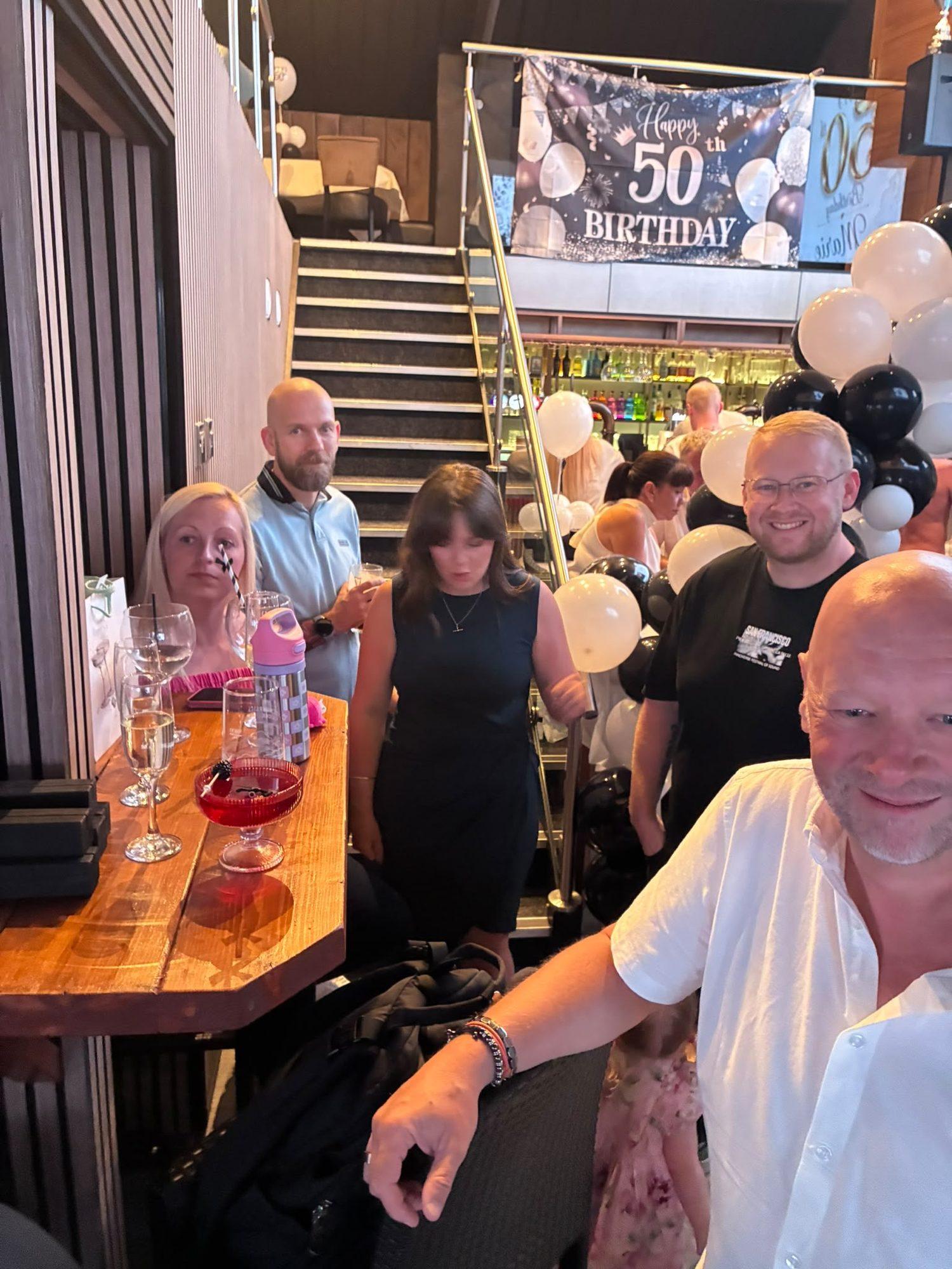 Party guests gathered by the staircase under a 50th birthday banner at The Lounge Rotherham
